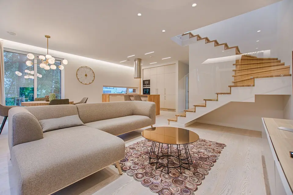 Sunlit living room with a beige sofa and wooden stairs