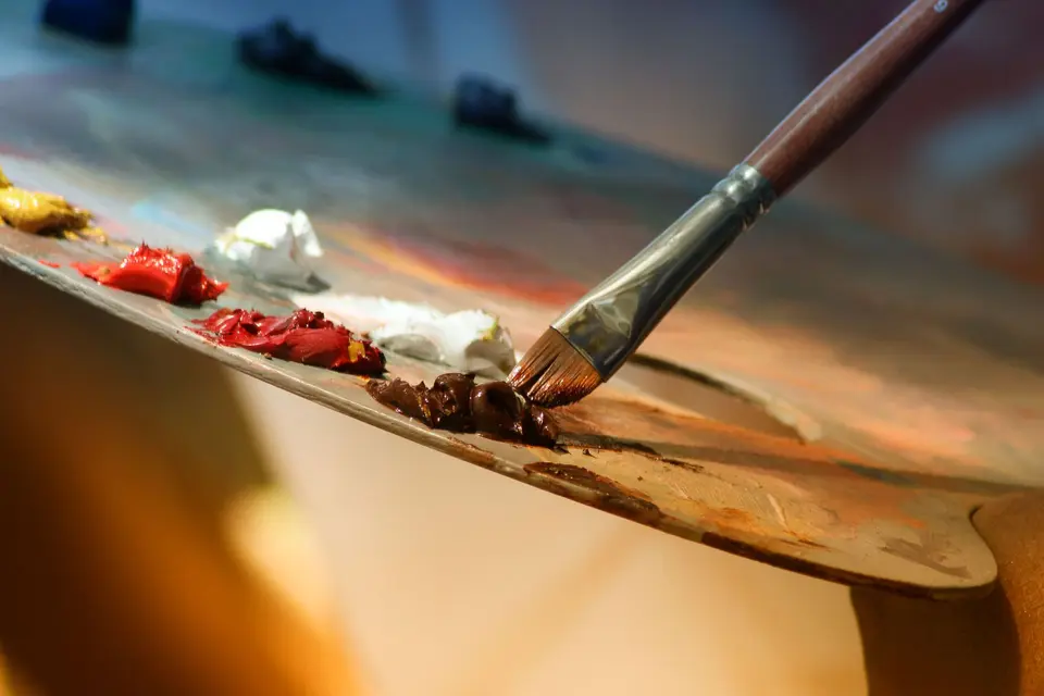 Paintbrush resting on a palette of bright paint