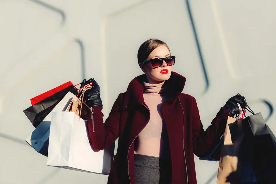 Person outdoors carrying paper shopping bags